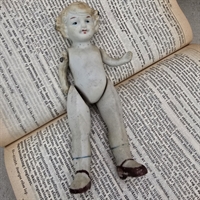 porcelænsdukke-kroellet-haar-blaa-sloejfe-sorte-sko-antik-dukke